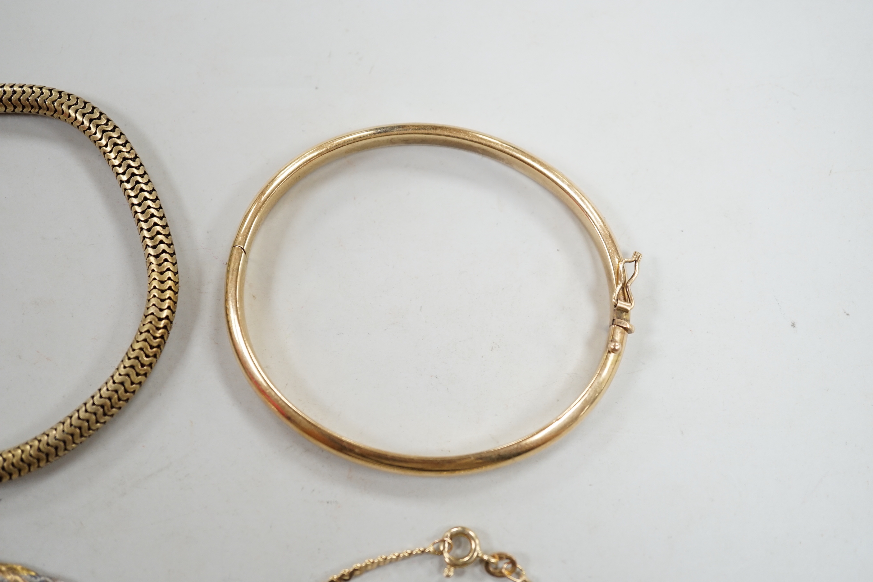 A modern 9ct gold hinged bangle, two modern 9ct gold bracelets including three colour, 14.4 grams and a yellow metal snake link bracelet.